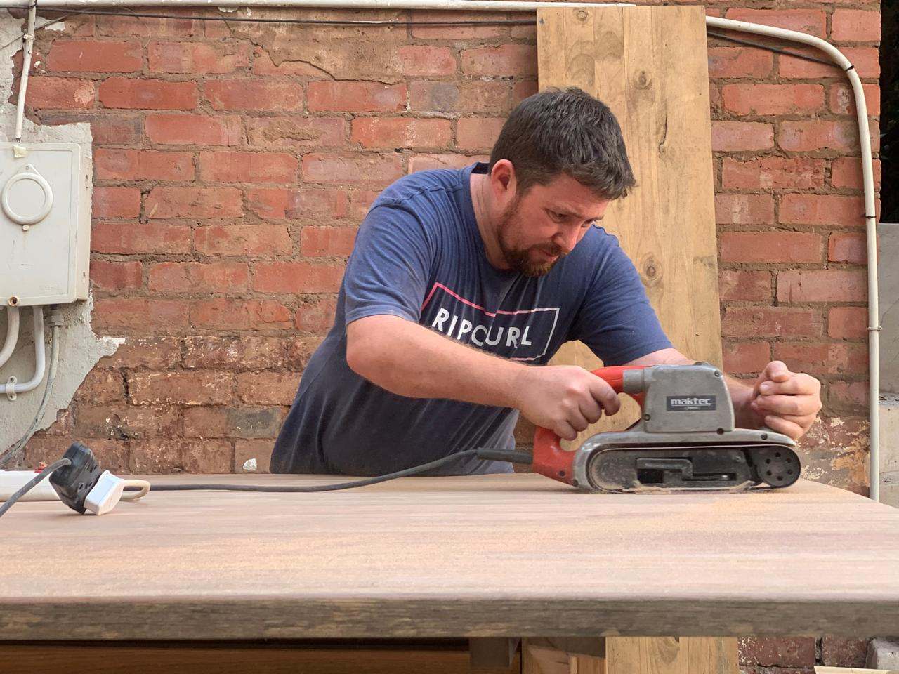 DG Technologies heritage entertainment room build detail: Hand Sanding the Hardwood Table
