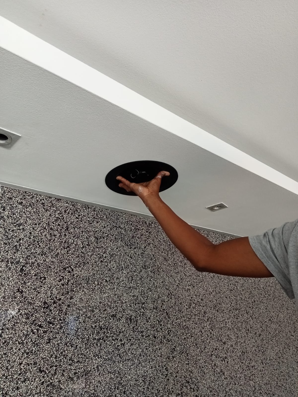 Technician fitting a ceiling speaker during first-fix and finishing work